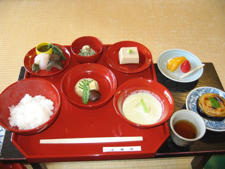 朱漆器皿中盛有米飯、豆腐與燉煮菜的春季精進料理