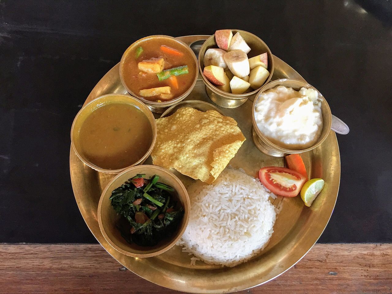 銅盤盛裝的尼泊爾豆湯飯，含米飯、豆湯、青菜與優格