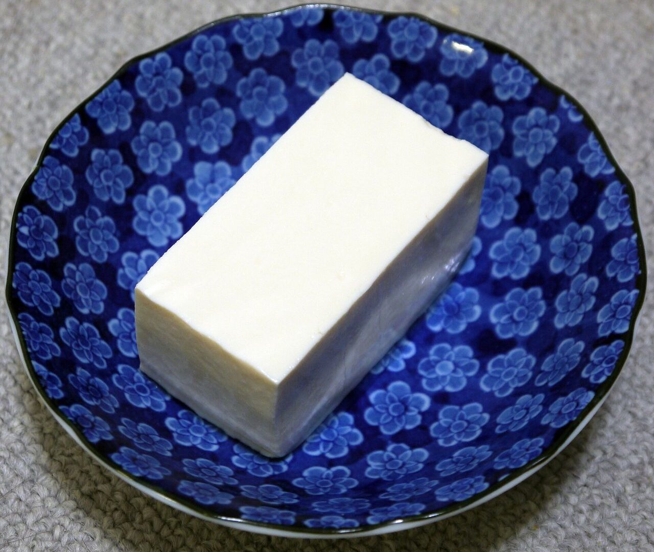 Một miếng đậu phụ mềm (kinugoshi) trong bát hoa xanh