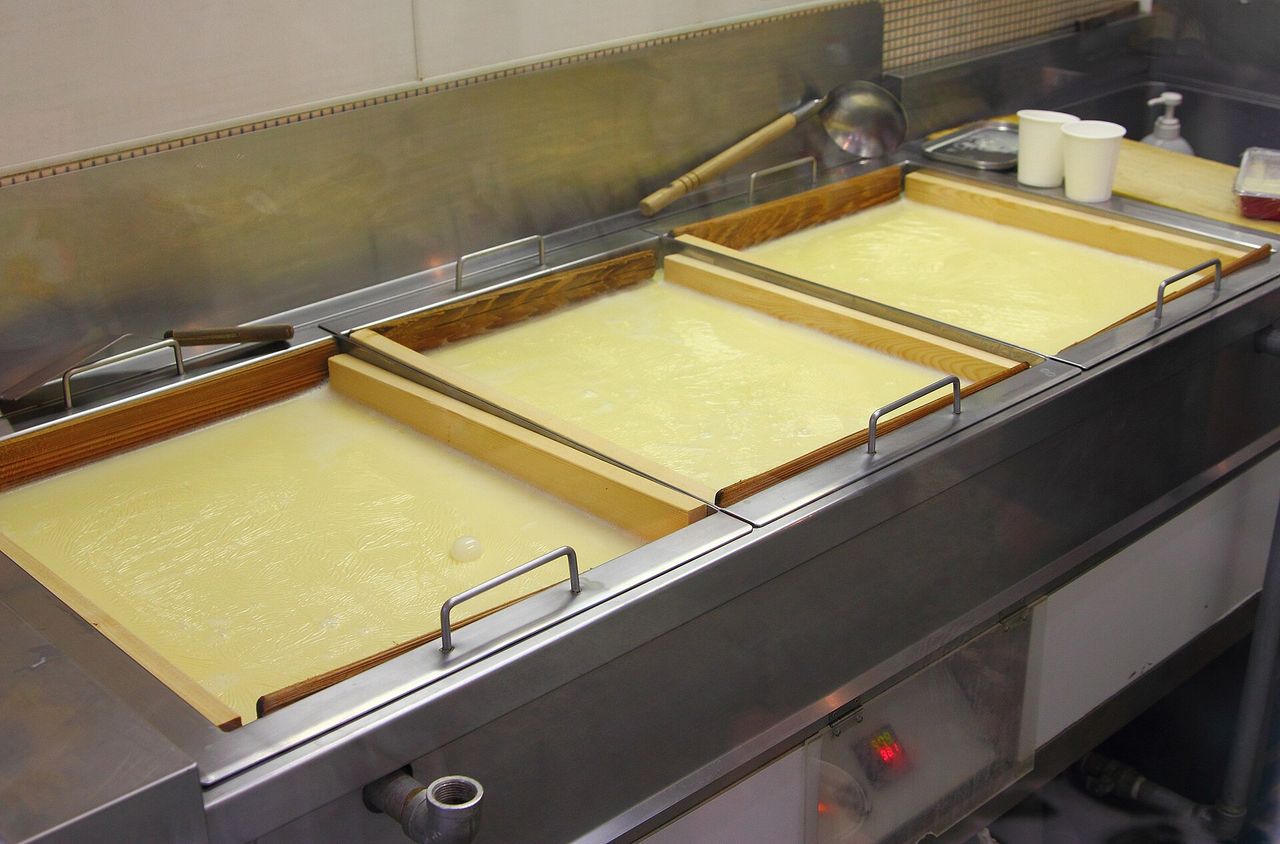 湯葉をつくる作業場で、湯葉槽に豆乳の膜が張っている様子