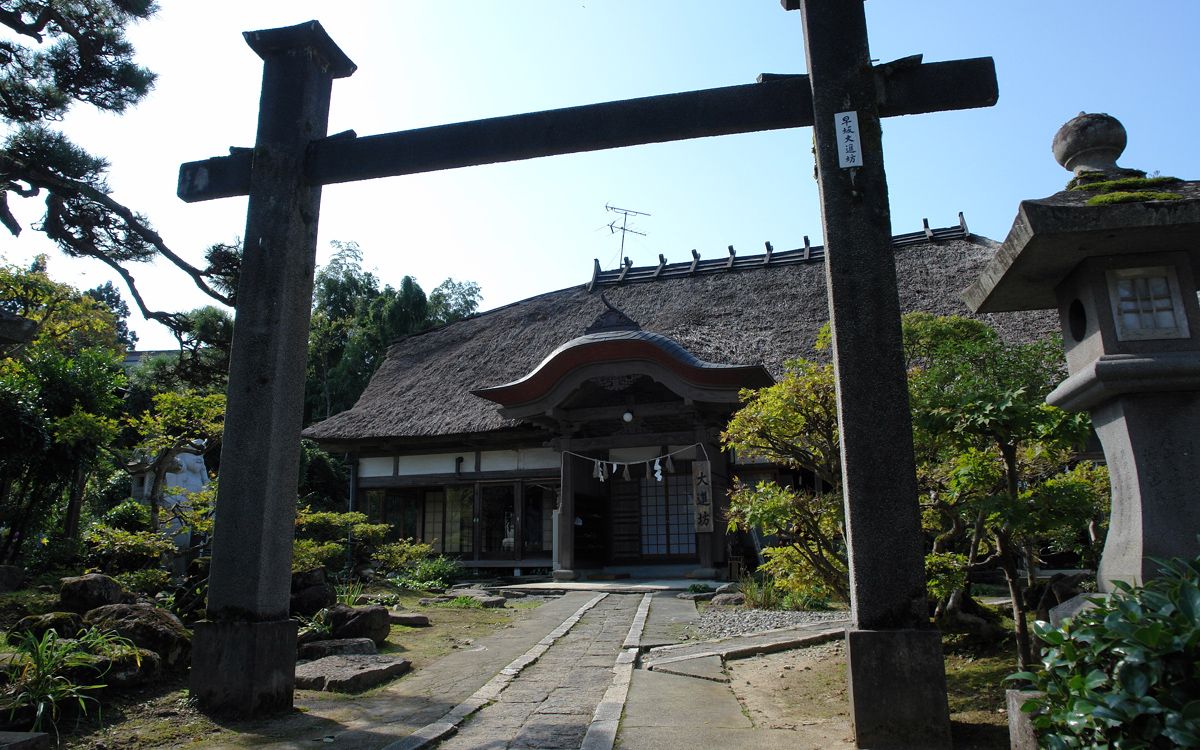 鳥居の奥に見える、茅葺き屋根の宿坊の建物